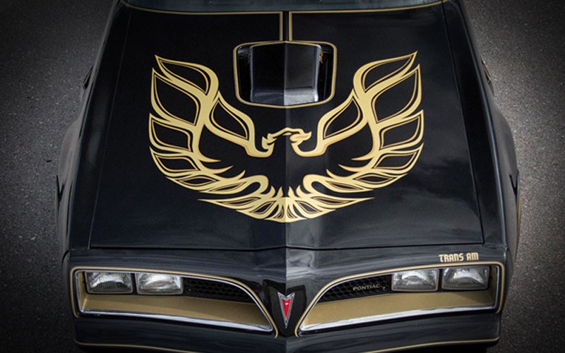 Burt Reynolds leaning on the hood of a black 1977 Pontiac Firebird Trans Am Special Edition in Smokey and the Bandit