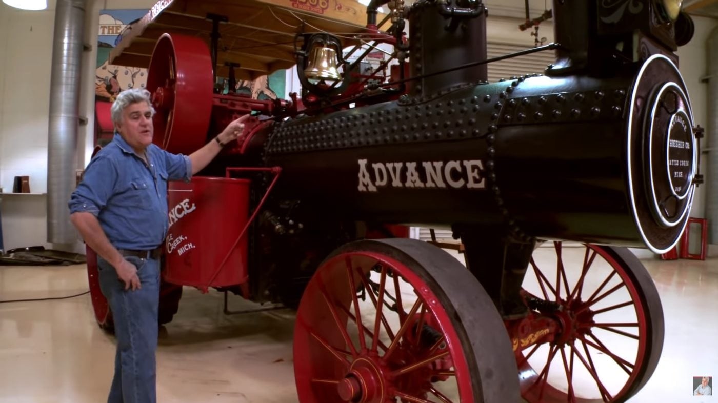 Jay Leno in his garage surrounded by classic cars