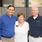 A caregiver stands between the franchise owners at her local office