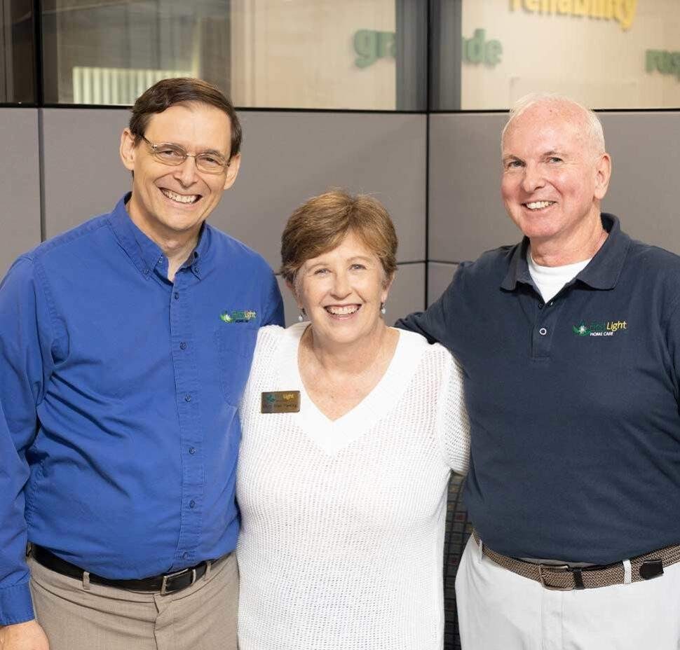 A caregiver stands between the franchise owners at her local office