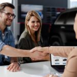 A car buyer shakes hands with a dealer after securing financing, illustrating the common scenario where a car lien is established to protect the lender's investment.