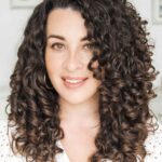 Woman smiling, showcasing defined curly hair, styled with treluxe products