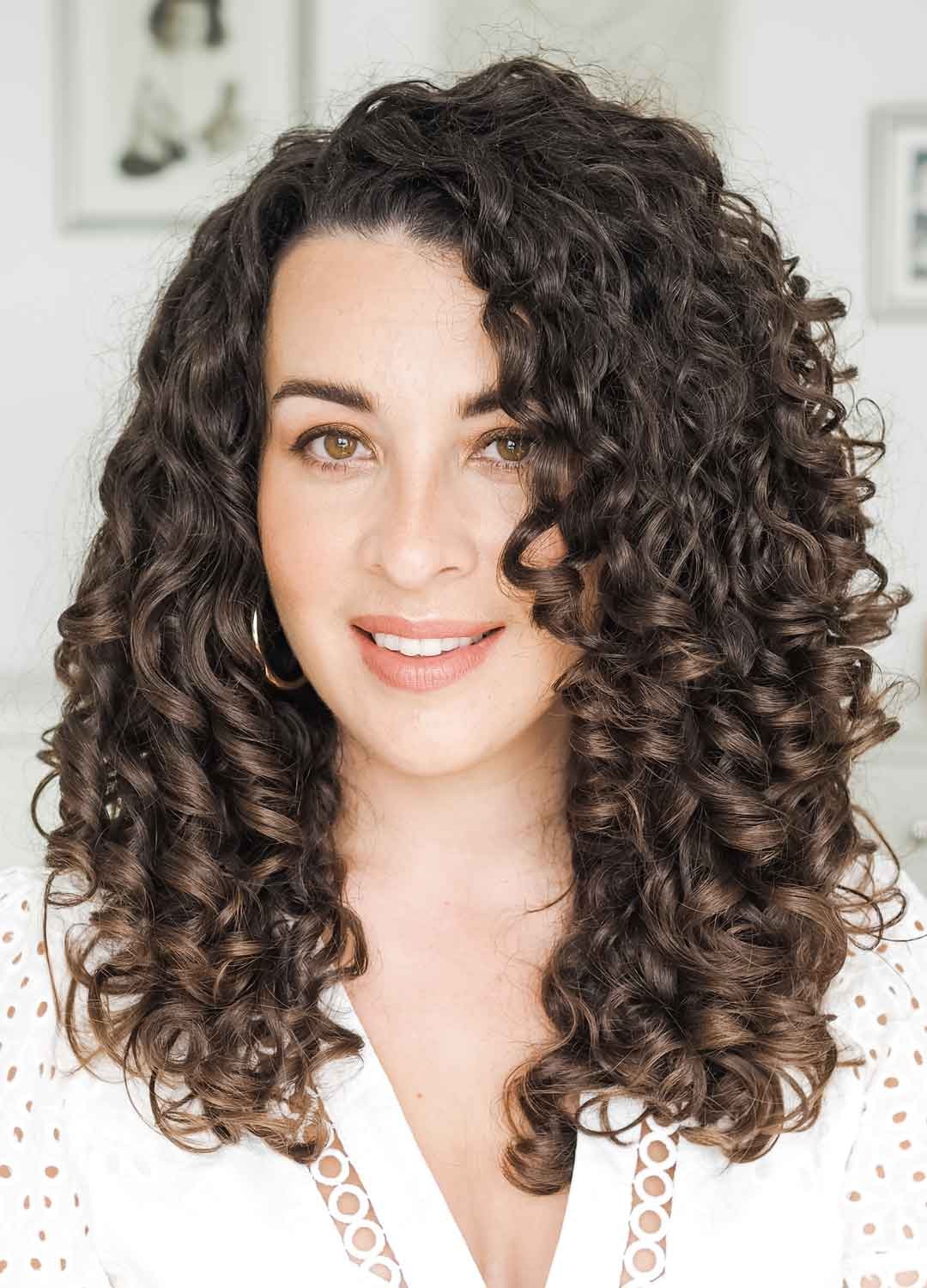 Woman smiling, showcasing defined curly hair, styled with treluxe products