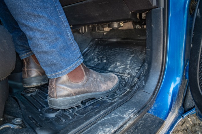 Boots on top of a passenger side rubber car floor mat, showing traction design