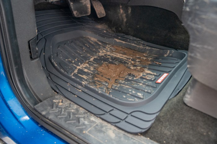 Mud and debris contained by the raised edges of a truck floor mat