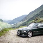 British Racing Green BMW E36 M3 GT parked on a scenic road, showcasing its sporty profile and rear wing