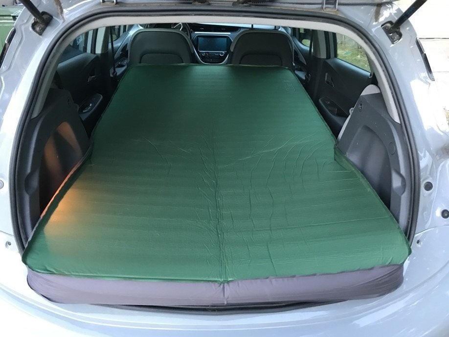 Chevrolet Bolt interior with Exped MegaMat Duo mattress fully extended showing trunk space and vehicle hood