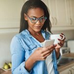 Smiling young woman in glasses using a smartphone for a virtual doctor's appointment