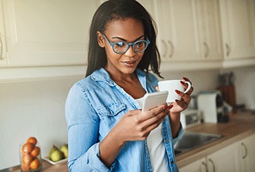 Smiling young woman in glasses using a smartphone for a virtual doctor's appointment