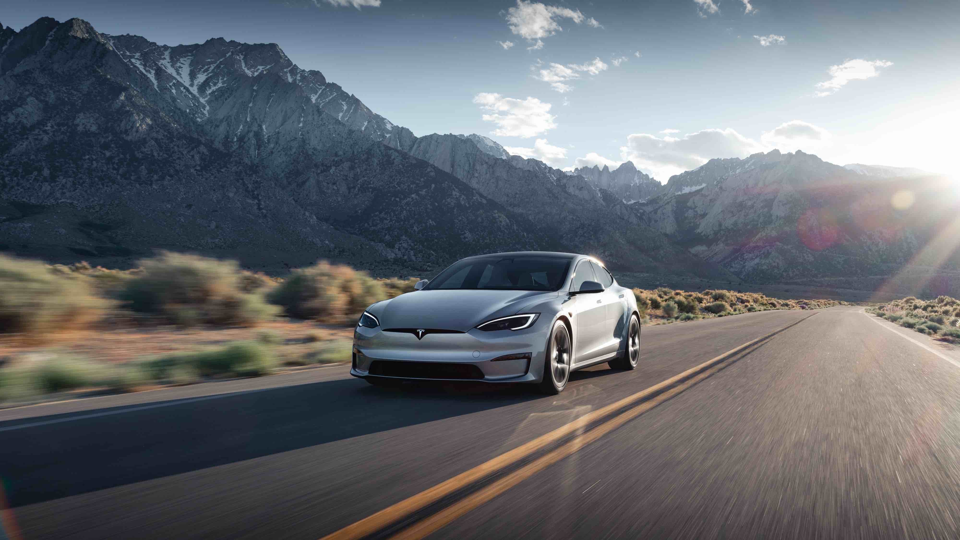 Silver Tesla Model X driving down a mountainside highway