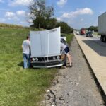 Breakdown of a vintage silver BMW on the roadside, highlighting the potential for unexpected repairs when owning a classic car.