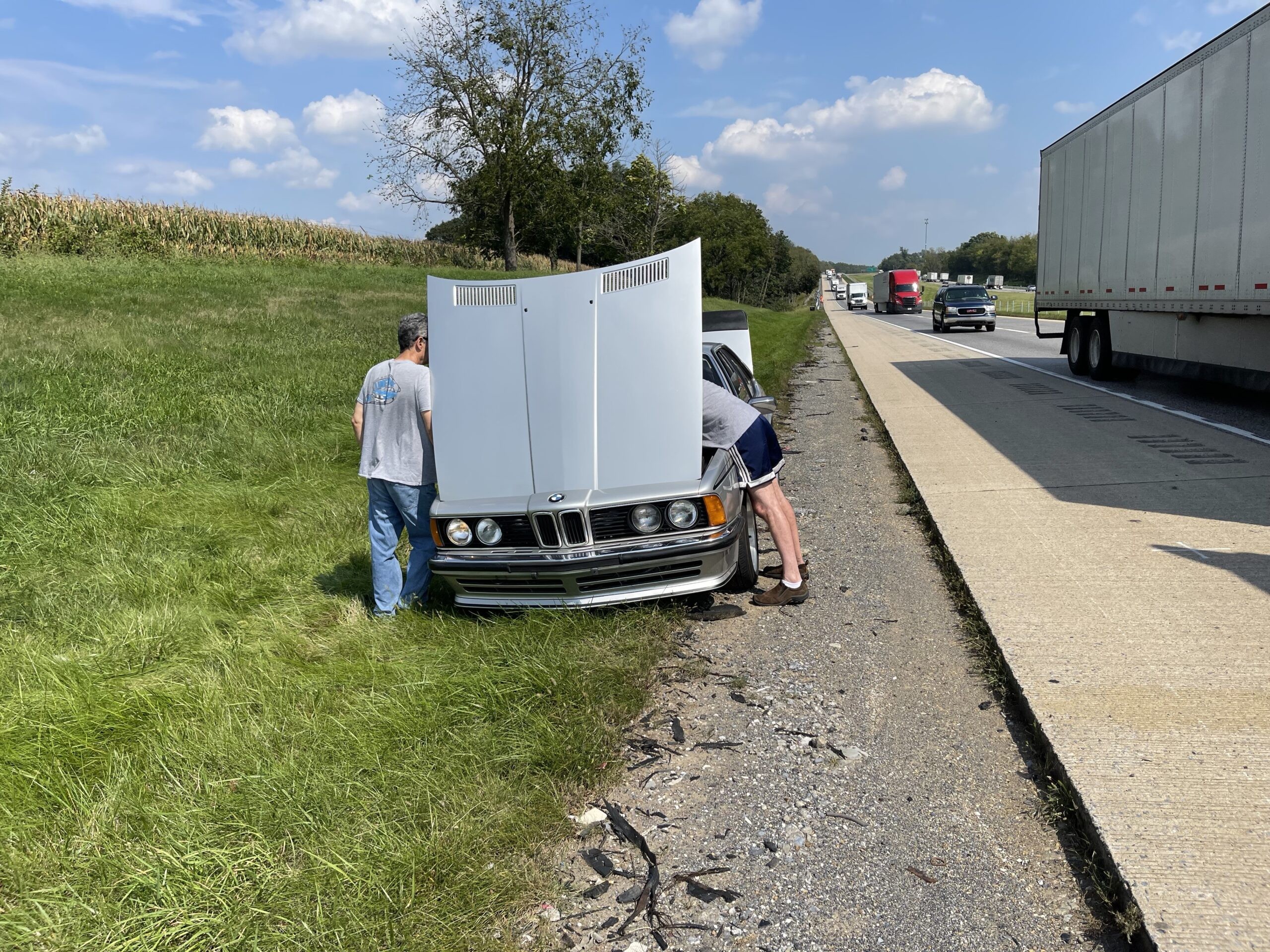 Breakdown of a vintage silver BMW on the roadside, highlighting the potential for unexpected repairs when owning a classic car.