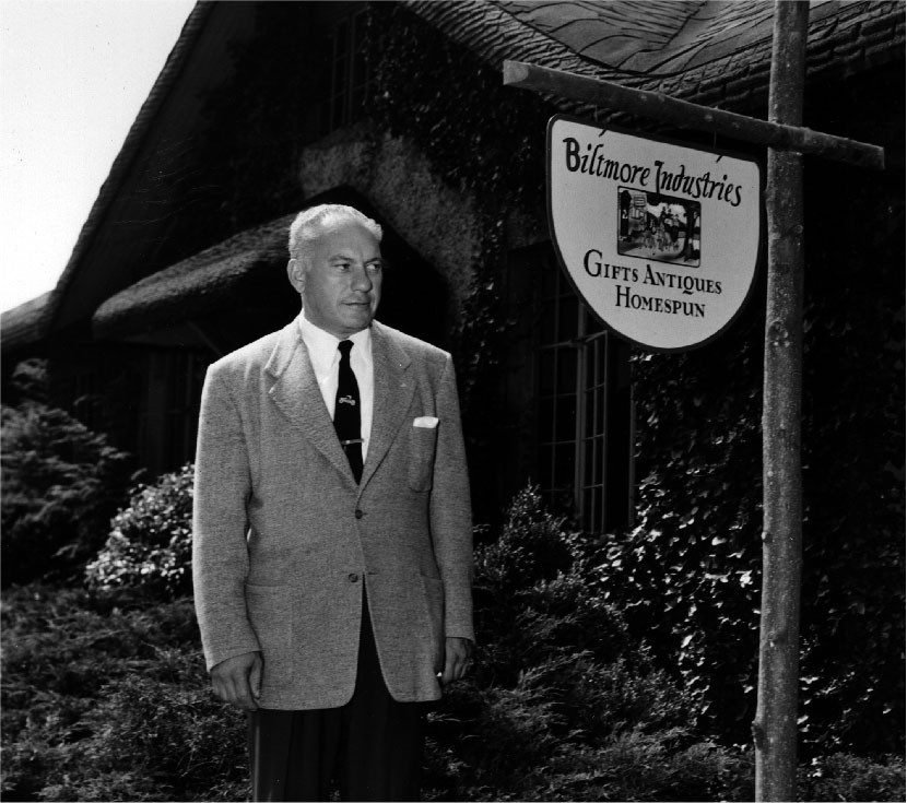 alt text: Harry Blomberg standing next to an antique car inside his museum at Grovewood Village