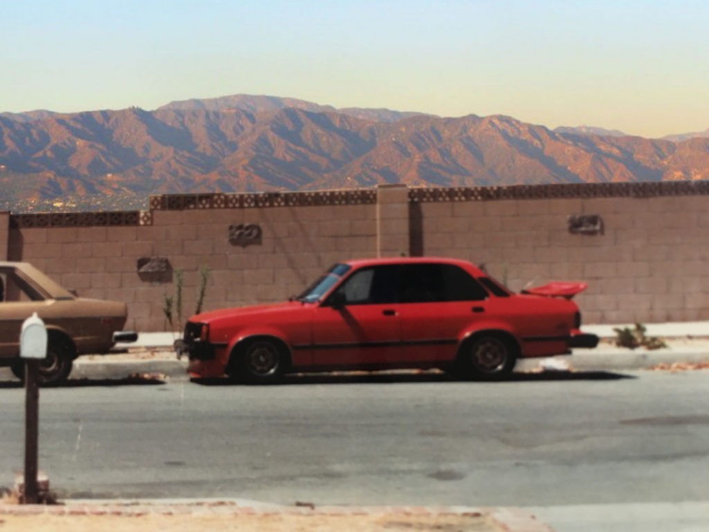 Isuzu I-Mark sedan with custom red paint job and aftermarket wing