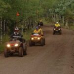 Three riders on dirt road with OHVs