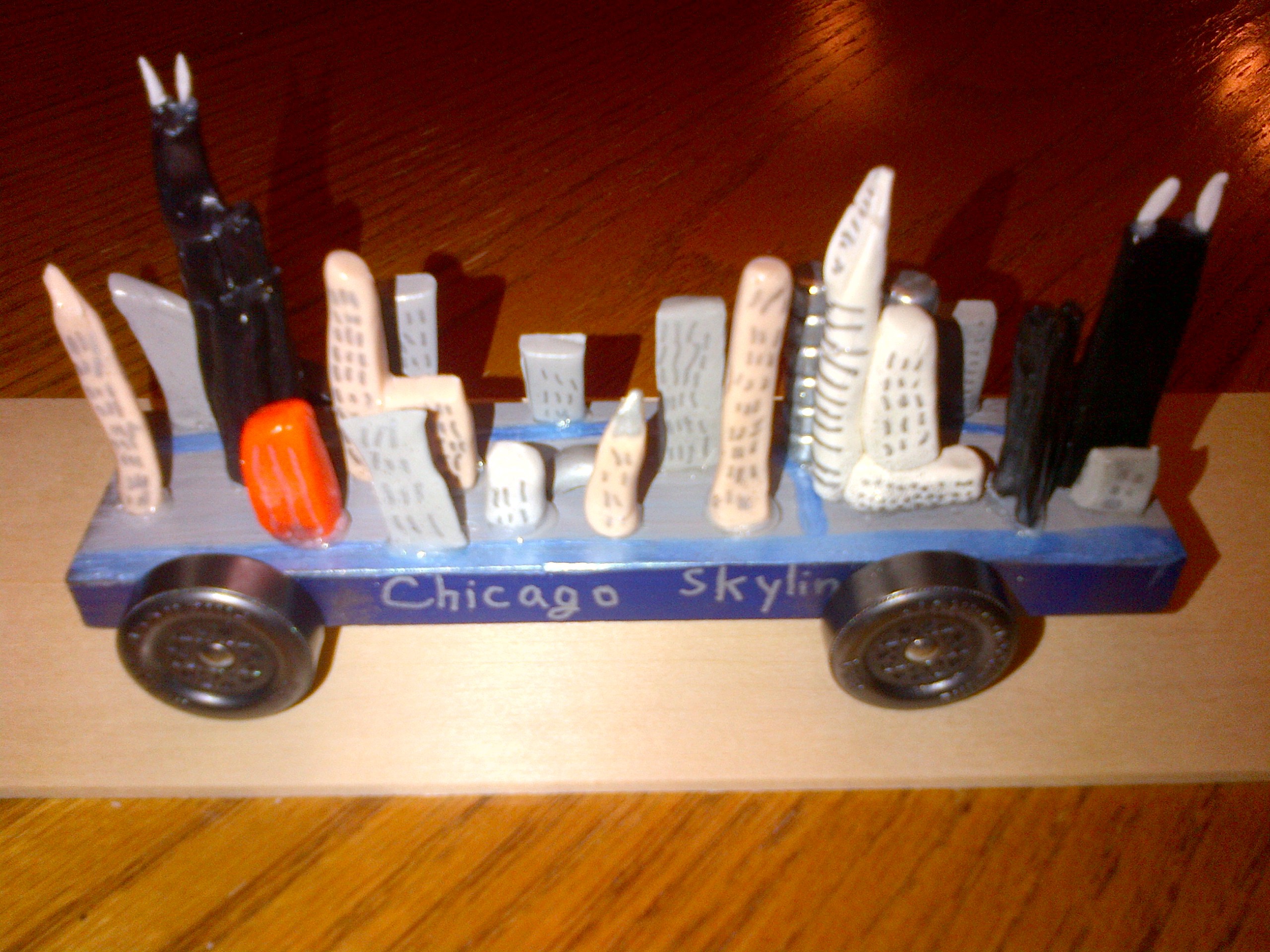 Close-up of a Chicago skyline pinewood derby car, emphasizing the detailed craftsmanship and fragile nature of the design, highlighting the need for pinewood derby care.