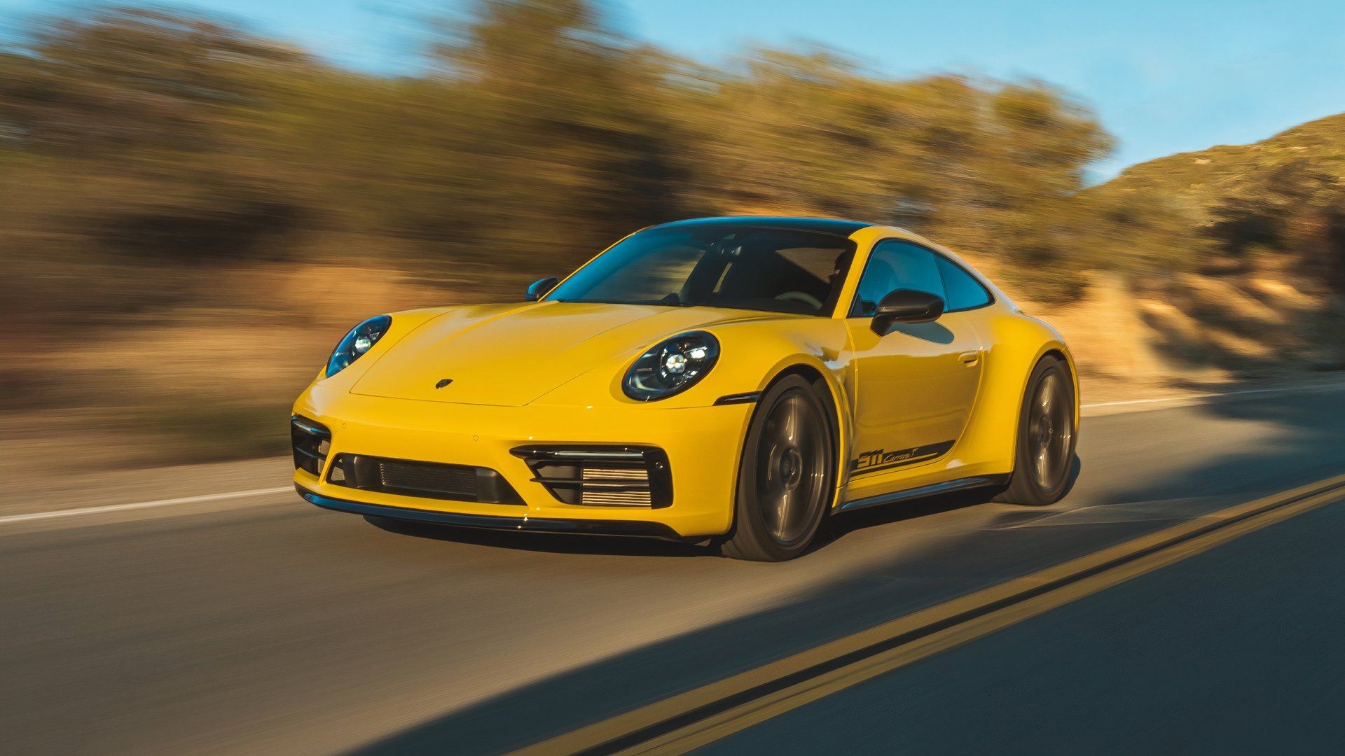 Front three-quarters action shot of a Porsche 911 Carrera T finished in Racing Yellow