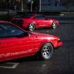 A pristine red Toyota AE86 GT-S coupe parked outdoors, showcasing its classic 80s design and SSR Longchamp XR-4 wheels.