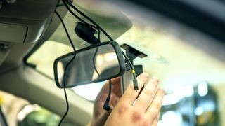 Hands installing a car dash camera into a car