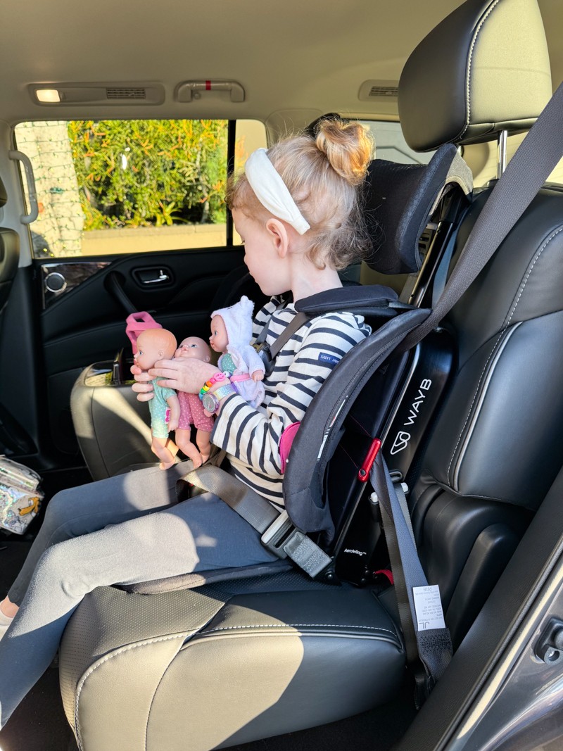 A toddler securely fastened in a WayB Pico lightweight and portable car seat, highlighting its suitability for travel.