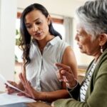 Young woman assisting senior with paperwork, symbolizing health care proxy discussions