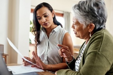 Young woman assisting senior with paperwork, symbolizing health care proxy discussions